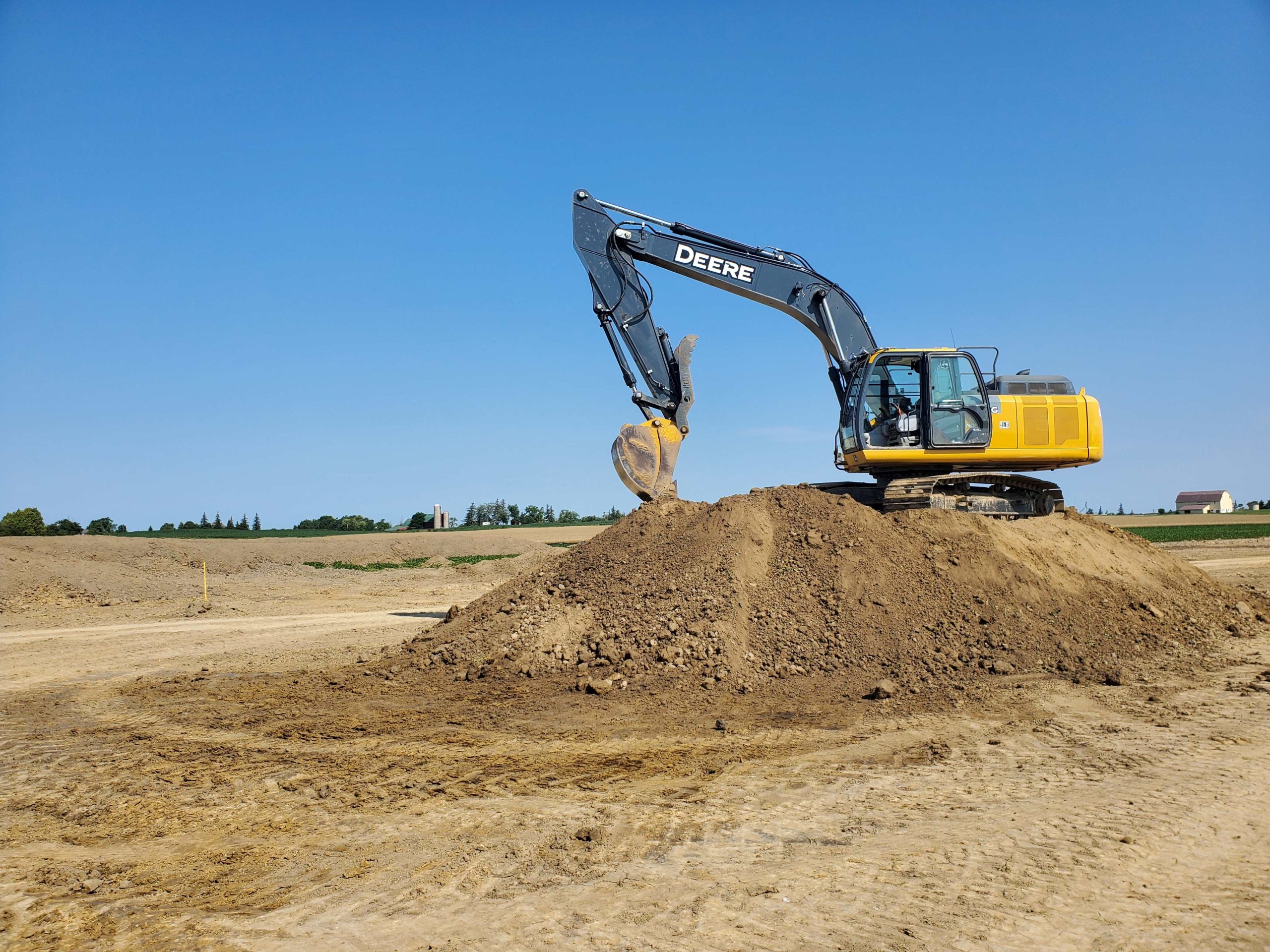 Excavator handling topsoil excavation — Hamilton site prep